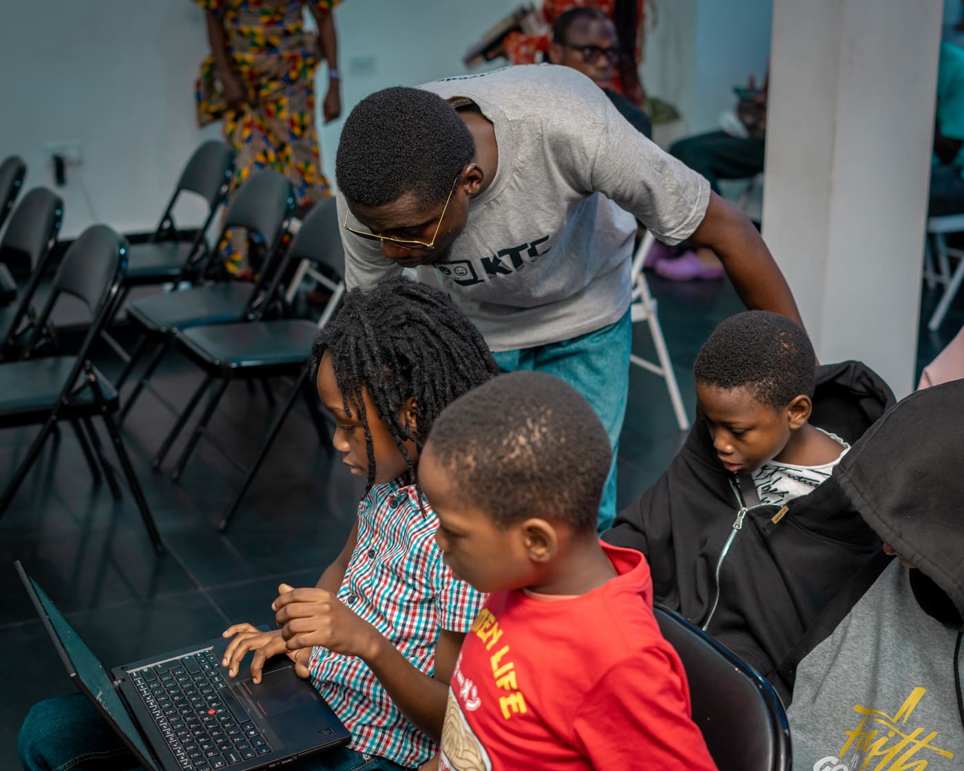 A mentor leaning in to help two students